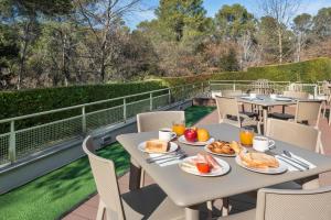 einen Tisch mit Teller mit Speisen auf einer Terrasse in der Unterkunft B&B HOTEL Barcelona Sant Cugat in Sant Cugat del Vallès