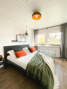 um quarto com uma cama com almofadas laranja e verde em Ferienhof Bannick em Bistensee