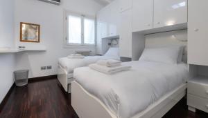 two beds in a bedroom with white walls and wood floors at Italianway Comfort - Torino 57 B in Milan