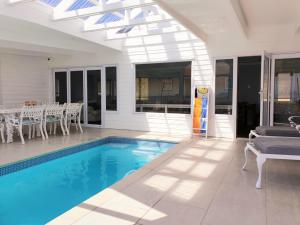 a swimming pool in a house with a table and chairs at 'The Bolussi Beachhouse', sleeps 12 in 6 en-suite bedrooms with Indoor Pool in Gordonʼs Bay +21 photos