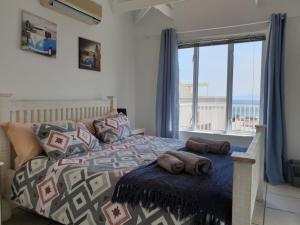 a bedroom with a bed with a view of the ocean at 'The Bolussi Beachhouse', sleeps 12 in 6 en-suite bedrooms with Indoor Pool in Gordonʼs Bay