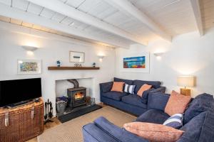 a living room with a blue couch and a fireplace at Sea Horses in Port Isaac