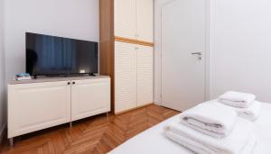 a bedroom with a flat screen tv and white towels at Italianway Comfort - Merlo 1 D in Milan