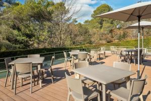 un patio con mesas, sillas y una sombrilla en B&B HOTEL Barcelona Sant Cugat, en Sant Cugat del Vallès