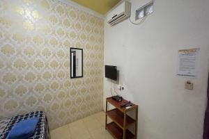 ein Schlafzimmer mit einem Bett und einem TV an der Wand in der Unterkunft OYO 93416 Wisma Alam Syariah in Mamuju