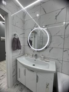 a white bathroom with a sink and a mirror at Яркая студия в новом доме in Oral