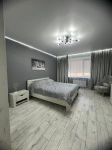 um quarto com uma cama e uma cadeira em Яркая студия в новом доме em Oral