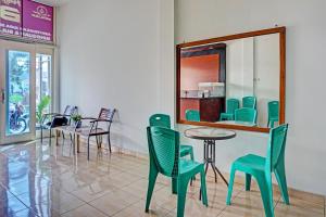 uma sala de jantar com cadeiras verdes e uma mesa em OYO 93264 Penginapan Syari'ah Berlian em Takengon