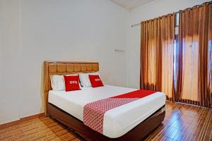 - une chambre avec un lit et des oreillers rouges dans l'établissement OYO 93264 Penginapan Syari'ah Berlian, à Takengon