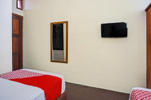a bedroom with a bed and a tv on a wall at OYO 93264 Penginapan Syari'ah Berlian in Takengon