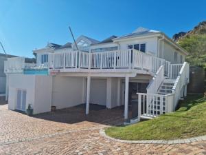 a large white house with a deck and stairs at 'The Bolussi Beachhouse', sleeps 12 in 6 en-suite bedrooms with Indoor Pool in Gordonʼs Bay