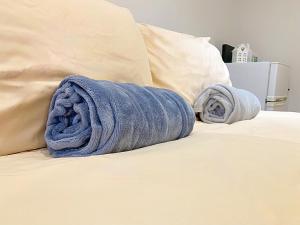 un asciugamano blu seduto su un letto con due cuscini di CozyTomari a Londra