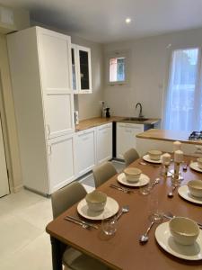 a kitchen with a wooden table with plates and silverware at Beach side apartment - Port-de-Bouc - logement entier in Port-de-Bouc