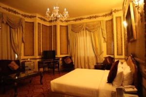 een hotelkamer met een bed, een bureau en een kroonluchter bij Windsor Palace Luxury Heritage Hotel Since 1906 by Paradise Inn Group in Alexandrië