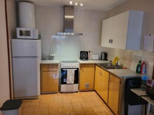 a small kitchen with white appliances and wooden cabinets at Apartamento Victoria, 300 m de la playa, 100 m centro in L'Estartit