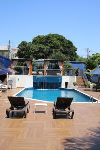a swimming pool with two chaise lounges in front of it at Hotel Portinari Centro in Foz do Iguaçu