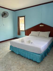 a large bed in a bedroom with a blue wall at Adam Bungalows in Krabi town