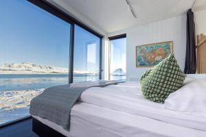 a bedroom with a large bed with a large window at The Oceanfront Private northern lights villa. in Reynivellir
