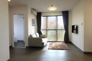 a living room with a couch and a chair and a window at Glenwood Suites in Ho Chi Minh City