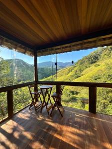 eine Veranda mit einem Tisch und Stühlen auf einem Berg in der Unterkunft Paraíso da serra in São Francisco Xavier