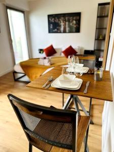 a wooden table with plates and wine glasses on it at Le Golden - Terrasse & Parking in Rennes