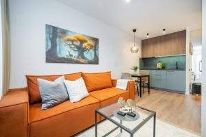 a living room with an orange couch and a kitchen at Apartments near Akropolis shopping center. in Vilnius