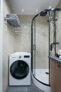 a washing machine in a bathroom with a shower at Apartments near Akropolis shopping center. in Vilnius