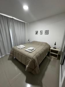1 dormitorio con 1 cama con 2 toallas en Departamentos y monoambientes Santiago 115 en Neuquén