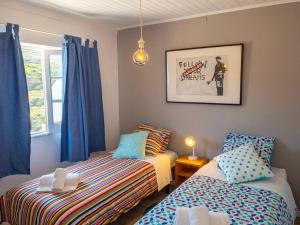 Un dormitorio con dos camas y una ventana con cortinas azules. en House beach in Lizandro by Ericeira Property, en Carvoeira