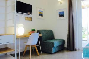 a living room with a chair and a desk and a tv at Cesarina Suite Apartment in Alessano
