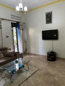 sala de estar con sofá y TV de pantalla plana en Tropical Oasis Retreat, en Kisubi