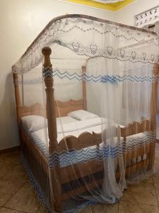 1 cama de madera con dosel en una habitación en Tropical Oasis Retreat, en Kisubi