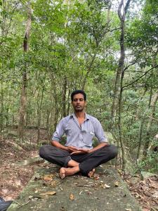 a man sitting on a rock in the woods at Tuktukraju Home stay 