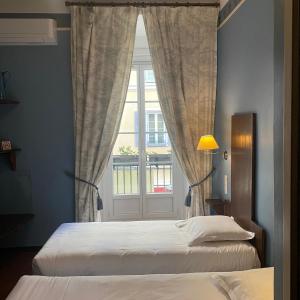 a bedroom with two beds and a window at Hotel Central Bastia in Bastia