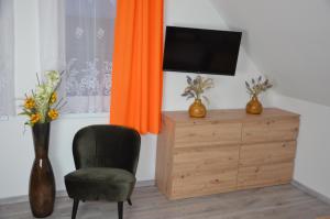 a room with a chair and a television and a wooden dresser at Apartmány Lukovské domečky in Lukov