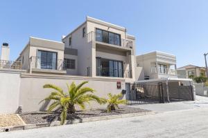 een wit huis met palmbomen ervoor bij Villa Balmoral 14 by HostAgents in Kaapstad