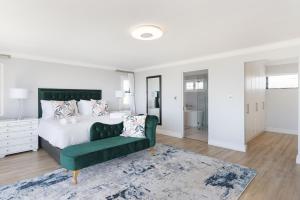 een slaapkamer met een bed en een groene bank bij Villa Balmoral 14 by HostAgents in Kaapstad