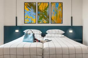 - une chambre avec un lit blanc et quatre peintures dans l'établissement Residenza Montebello, à Verbania