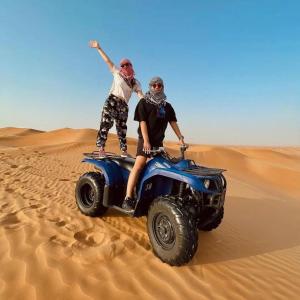 two people on a wheeler in the desert at Luxury Camp Camelhouse in Merzouga