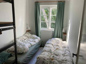 1 dormitorio con 2 literas y ventana en Charming Thatched-roof Cottage From 1947, en Dronningmølle