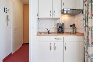 eine Küche mit weißen Schränken und einem Waschbecken in der Unterkunft Seepark Sellin FeWo AG Whg 321 in Ostseebad Sellin