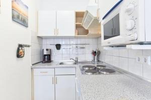 uma cozinha com armários brancos e um lavatório em Fewo 345, Seepark Sellin em Ostseebad Sellin