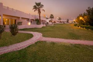 a walkway in front of a building with a palm tree at Copthorne Al Jahra Hotel & Resort in Kuwait