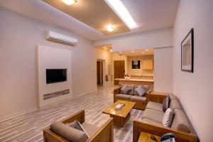 Copthorne Al Jahra Hotel & Resort في الكويت: غرفة معيشة مع كنب وتلفزيون بشاشة مسطحة