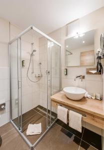 a bathroom with a glass shower and a sink at Die Post Hotel in Bad Grönenbach