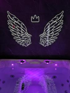 un cartel de neón con alas en la bañera en Le Spacidulé, en Saint-Amand-les-Eaux