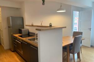 eine Küche mit einem Tisch, einem Kühlschrank und einer Spüle in der Unterkunft Lille centre - Beautiful bright apartment! in Lille
