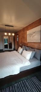 a bedroom with a large white bed with a wooden wall at Beach old fisherman's house in Jūrmala