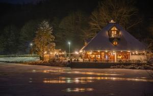 a building with a thatched roof at night at Hotel-Restaurant Eifeler Seehütte in Rieden
