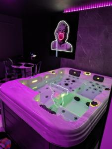 bañera de hidromasaje en una habitación con iluminación púrpura en Le Spacidulé, en Saint-Amand-les-Eaux